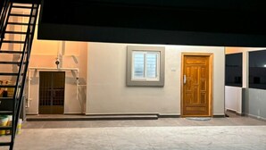 A modern building with a flat roof, a wooden door, and a window. - PS ELITE HOME STAY (Tirupati)