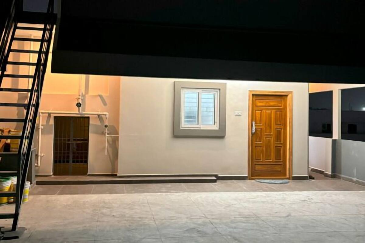 A modern building with a flat roof, a wooden door, and a window.