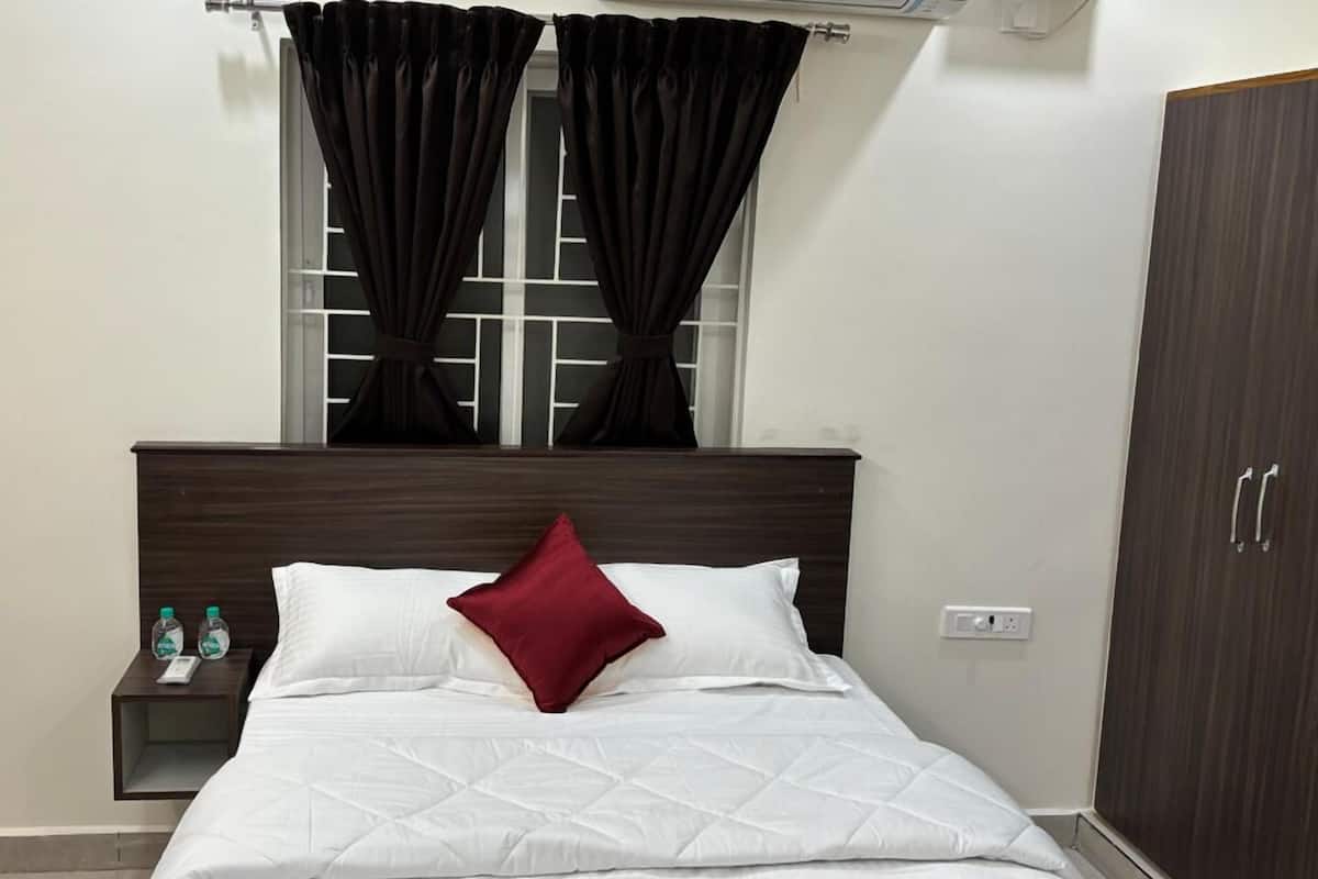 A hotel room with a bed, a nightstand, a wardrobe, and a window with curtains.