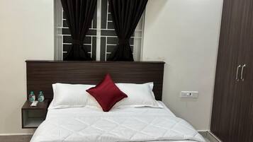 Een hotelkamer met een bed, nachtkastje, garderobe en een raam met gordijnen.