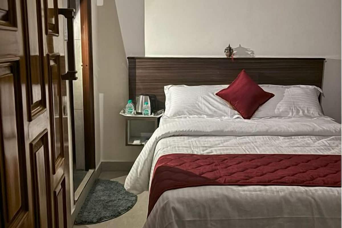 A hotel room with a bed, a nightstand, and a wooden door.