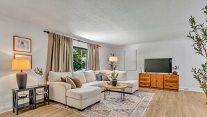 Ein modernes Wohnzimmer mit einer Eckcouch, einem Couchtisch, einem Fernseher und einem Holzschrank.