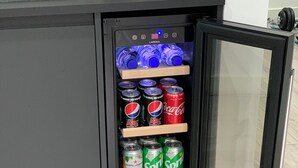 Un mini-réfrigérateur rempli de diverses boissons, notamment du Pepsi, du Coca-Cola, du Sprite et du Tango.