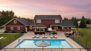 Ein großes Haus mit Swimmingpool, Sitzgelegenheiten im Freien und einer überdachten Terrasse.