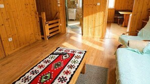 A wooden interior with a sofa, a patterned rug, and a bench.