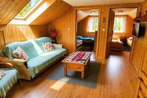 A cozy cabin with a loft bedroom, a sofa, and a wooden floor.