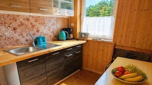 A kitchen with a wooden countertop, a sink, a stove, and a window with a view of greenery.
