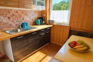 A kitchen with a wooden countertop, a sink, a stove, and a window with a view of greenery.