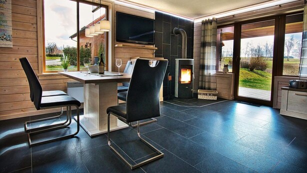 Una cocina moderna con un ventanal grande, una chimenea y una zona de comedor con sillas y una mesa.