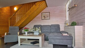 Una sala acogedora con un sofá seccional gris, una mesa de centro de madera y una escalera.