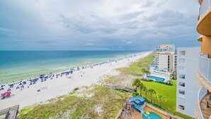 A beach view with a resort building, including a pool and a deck area. - Poolside Vibes & Lazy River Days Phoenix Orange Beach 603 (Orange Beach)