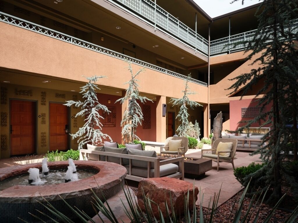 A courtyard with a fountain, seating area, and potted trees.