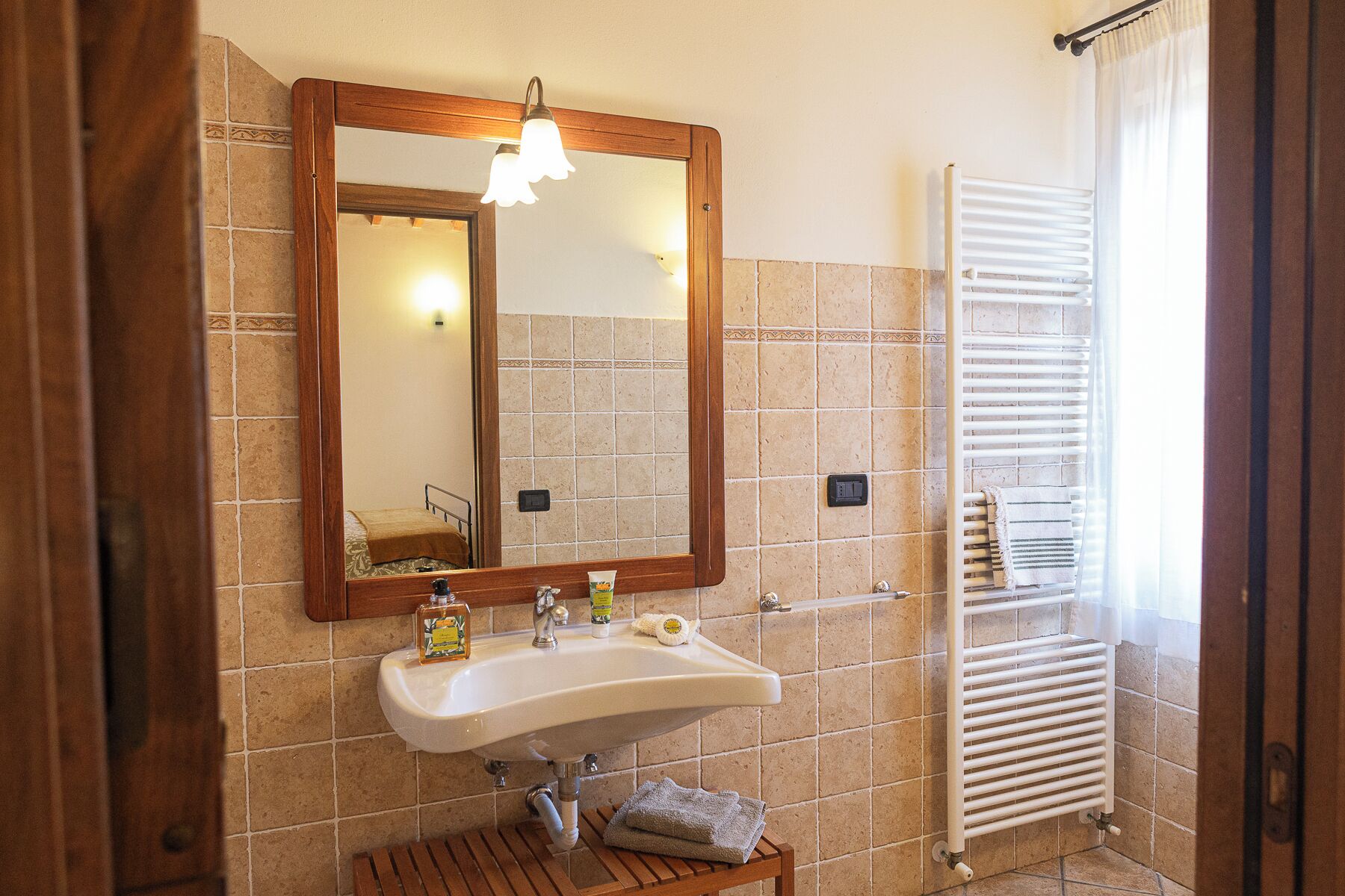 A bathroom with a wooden-framed mirror, a white sink, and a towel rack.