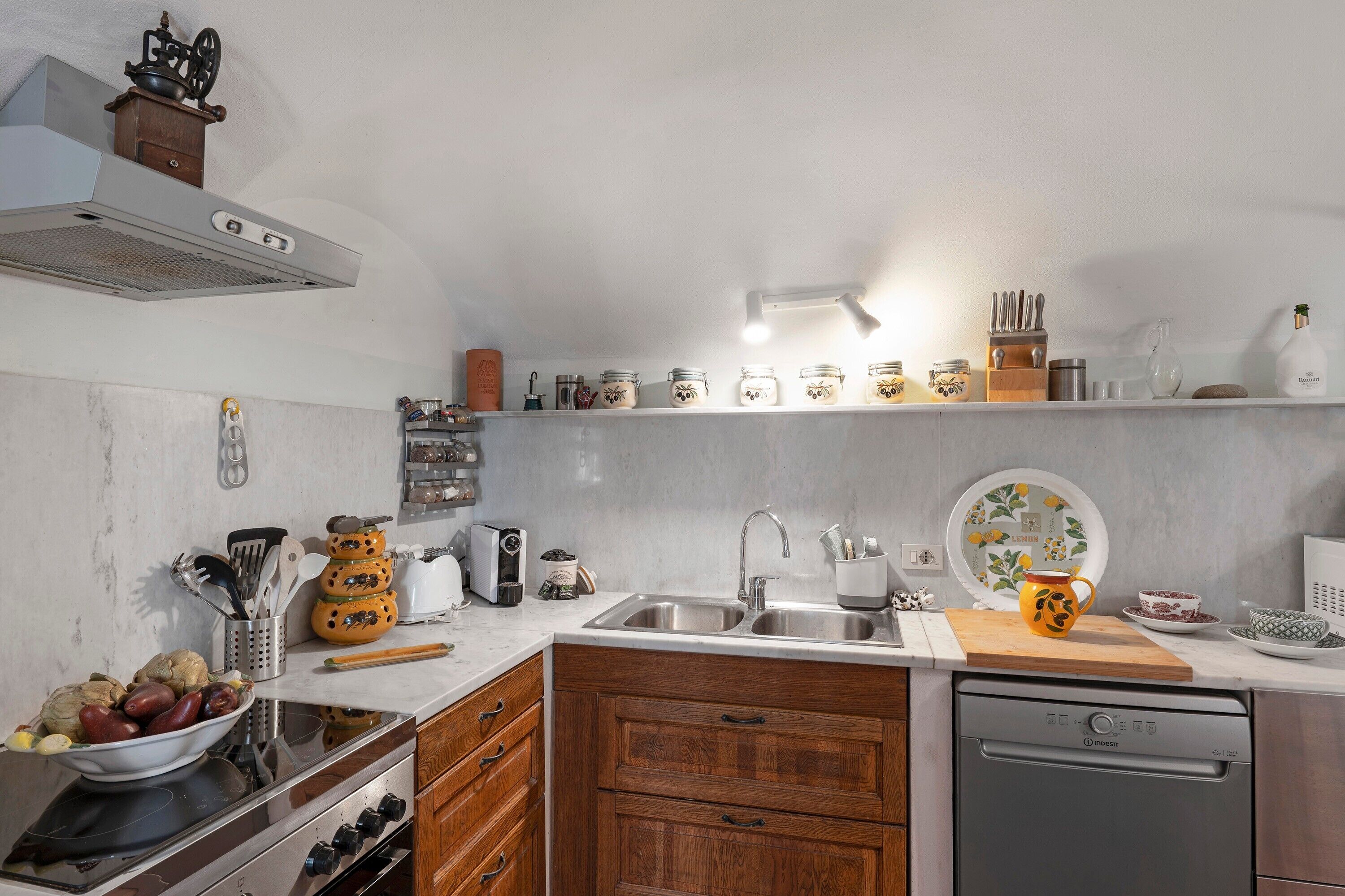 Una cocina con lavavajillas, doble pileta, muebles de madera y una variedad de utensilios y electrodomésticos.