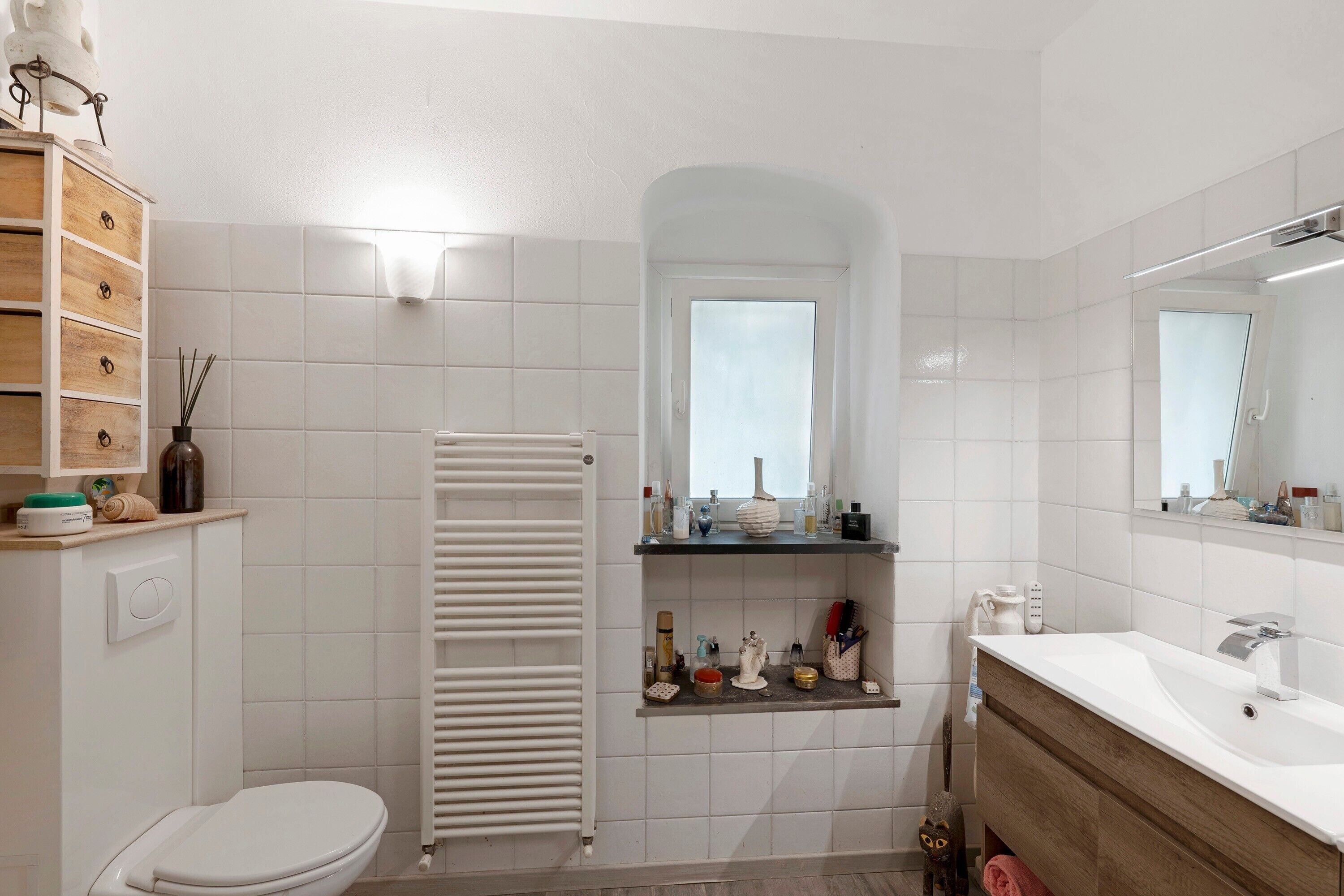 Ein Badezimmer mit Toilette, Handtuchhalter, Spiegel und Ablagen für Toilettenartikel.