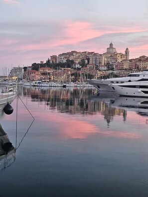 Un port de plaisance avec des bateaux, une eau calme et un paysage urbain avec des bâtiments en arrière-plan.