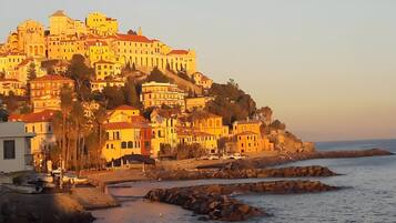 A coastal town with buildings on a hillside, a beach, and rocky outcrops.