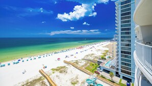 A beach resort with a clear view of the ocean, a sandy beach, and a modern building with balconies.