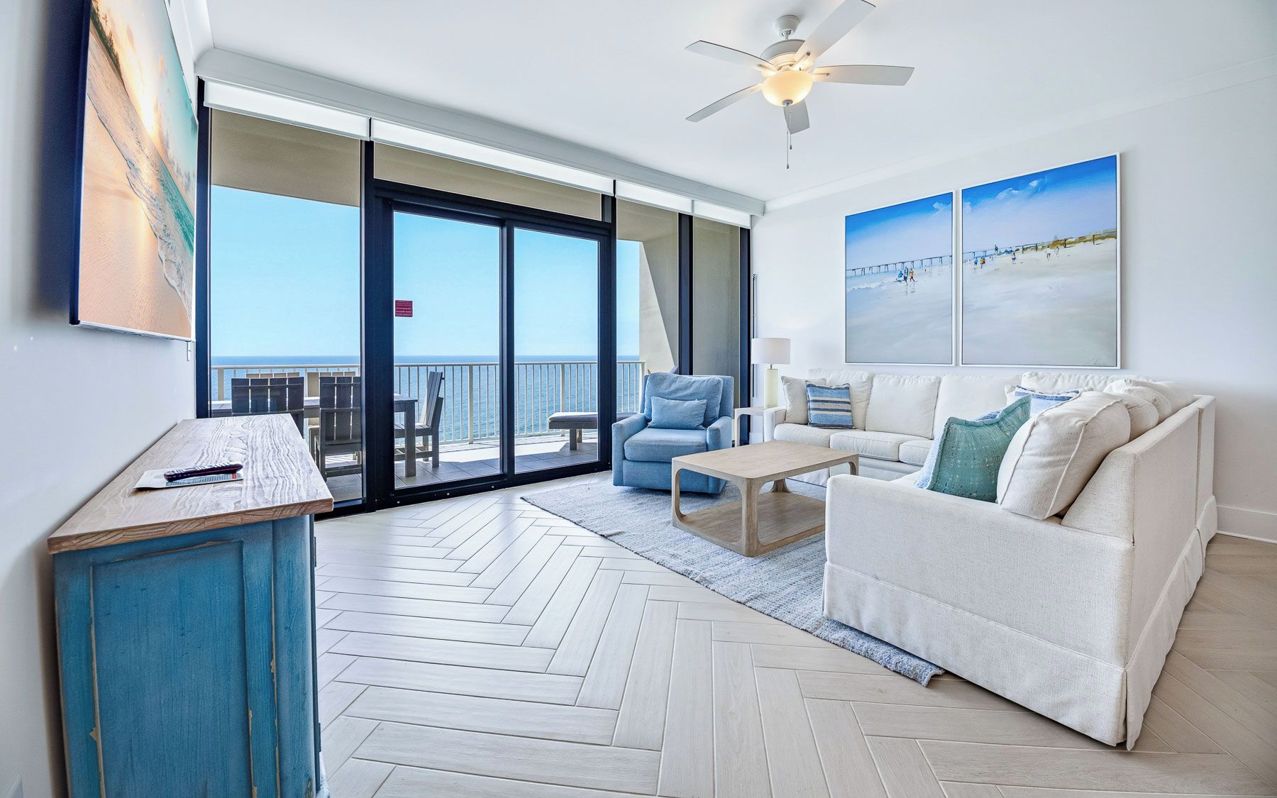 A spacious living room with a large sliding glass door leading to a balcony with a view of the ocean.