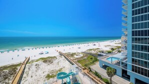 A beach view from a high-rise hotel with a pool and a water slide.