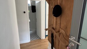 A hallway with a wooden door, a glass door, and a tiled floor.