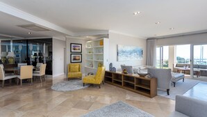 A spacious living room with a dining area, a large window with a city view, and a modern interior design.
