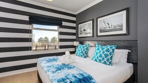 A hotel room with a bed, a window with a view, and two framed pictures on the wall.