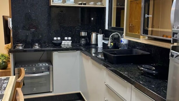 A compact kitchen with a black countertop, white cabinets, and a built-in oven.