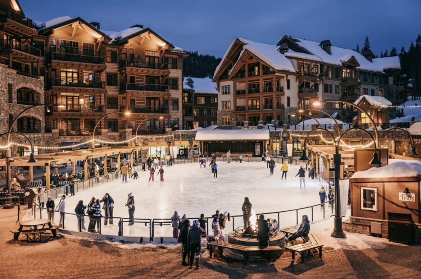 A multi-story hotel with a central ice rink surrounded by outdoor seating areas and shops.