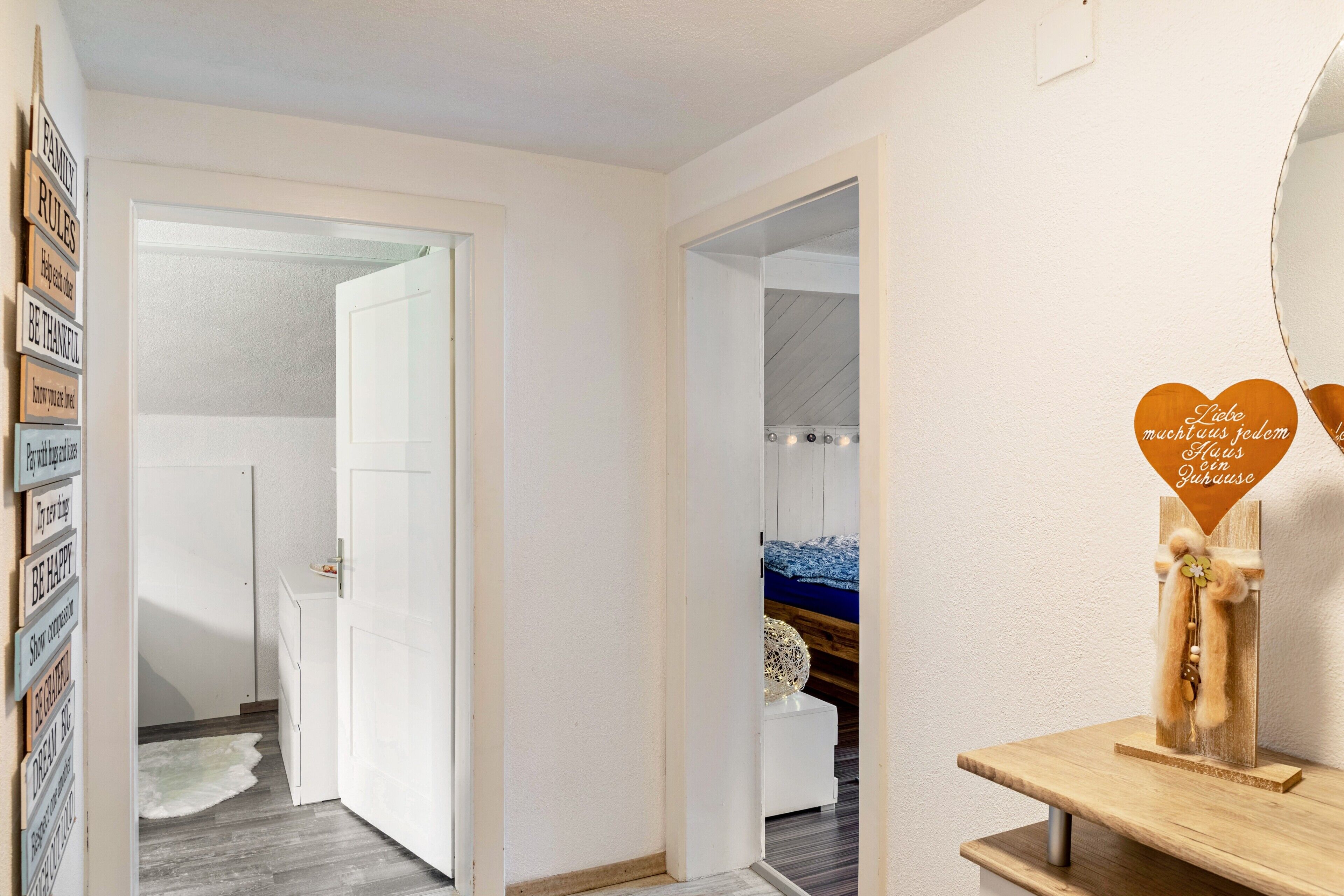 En hall med en vit dörr, en spegel och en hylla med dekorativa föremål.