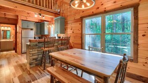 L’intérieur d’une cabane en bois comprend un coin repas, une cuisine et de grandes fenêtres.