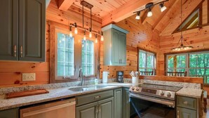 L’intérieur d’un chalet en bois comprend une cuisine équipée de plans de travail en granit, d’une cuisinière et d’un évier.