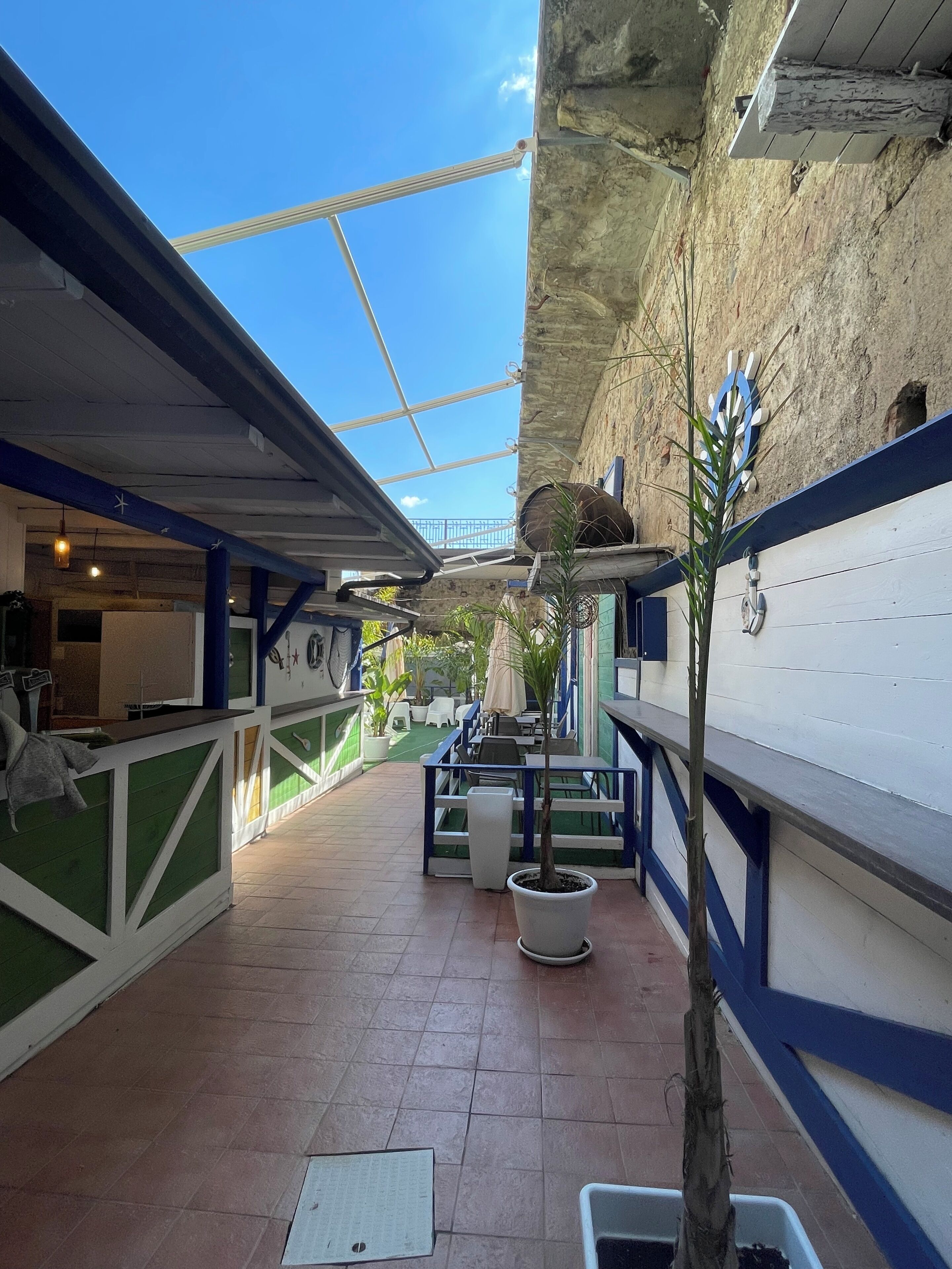 Un patio al aire libre con suelo de baldosas, plantas en macetas y mobiliario exterior.