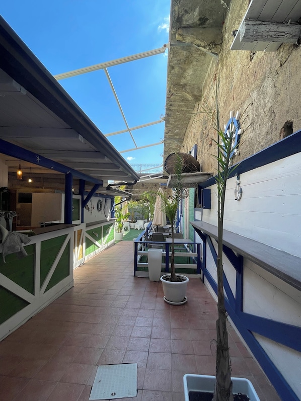An outdoor patio area with a tiled floor, potted plants, and outdoor seating. - Marina Club (Giardini Naxos)