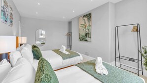 A modern hotel room with a large bed, a bedside table, a mirror, a wall-mounted TV, and a plant. - Hove Alone 5 | Top Floor | By My Getaways (Hove)