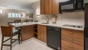 Una cocina moderna con armarios de madera, lavavajillas integrado, microondas y un lavamanos.