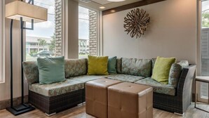 A modern living room with a sectional sofa, a floor lamp, and a decorative wall piece. - Jekyll Island Getaway | Free Parking | Free Breakfast | Ouytdoor Pool Access (Jekyll Island)