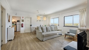 A spacious living area with a sofa, a dining table, and a kitchen in the background. - Luzia Apartment in Tavira (Tavira)