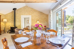 A dining area with a wooden table set for four, a vase of flowers, and a fireplace.