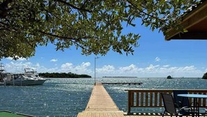 Une terrasse en bois offrant une vue sur l’eau, une table de billard et des sièges d’extérieur.