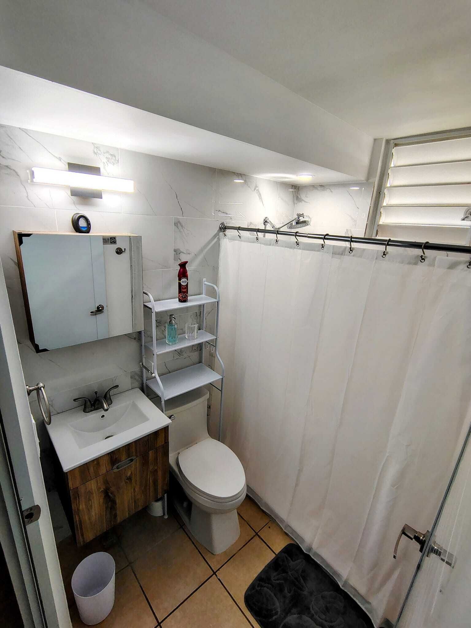 A compact bathroom with a toilet, sink, and shower area.