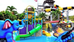 Un parc aquatique doté de divers toboggans et d’aires de jeux, notamment un toboggan en forme d’éléphant bleu et un toboggan en forme de papillon.