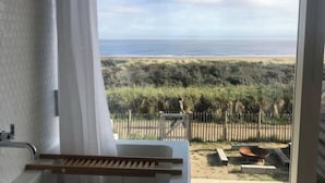 Un balcón con vista a la playa, un banco de madera y un pequeño hogar para fuego.