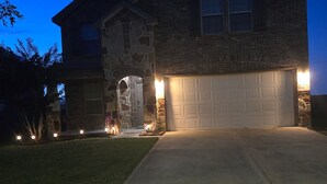 A two-story house with a stone facade, a garage, and a well-lit driveway at dusk. - 4-bedroom house in welcoming Missouri City with WiFi, AC near NRG Stadium (Missouri City)