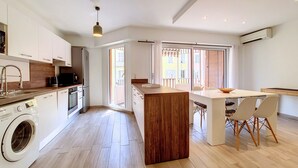 A modern kitchen with a central island, built-in appliances, and a dining area with a table and chairs.