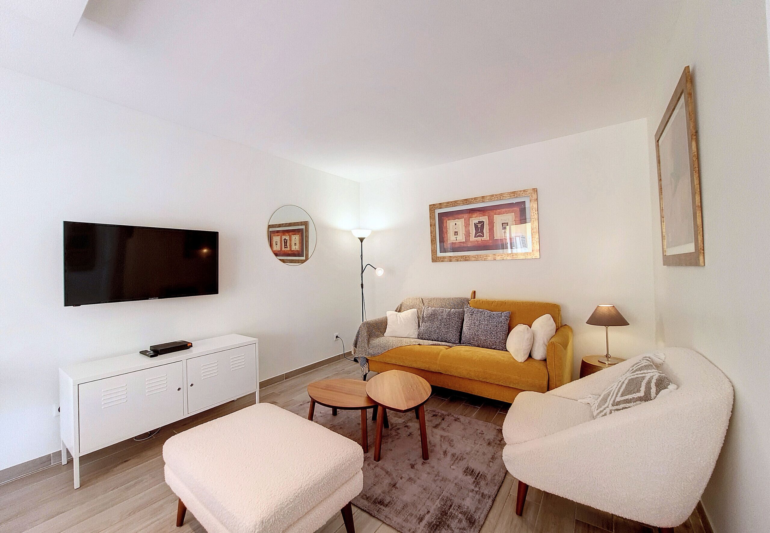 A modern living room with a sofa, two armchairs, a coffee table, a TV, a cabinet, and a floor lamp.