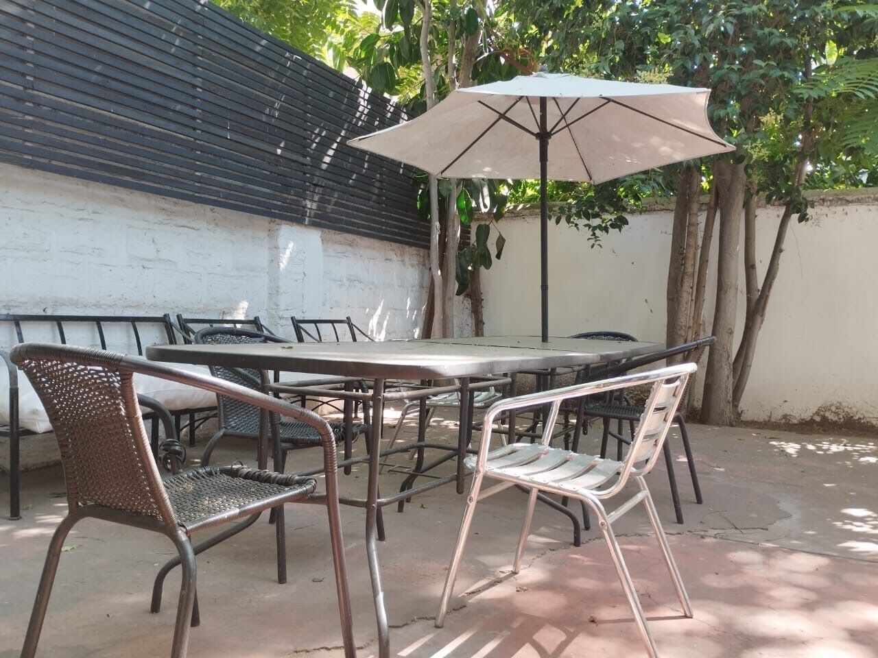 An outdoor patio with a table and chairs, an umbrella, and a tree.