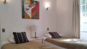 A room with two beds, a lamp, a painting, and a window with curtains. - Casa y patio en mejor barrio de Santiago (Santiago)