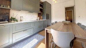 A modern kitchen with grey cabinets, a marble countertop, and a wooden dining table with chairs. - N&J - BELLE EPOQUE - Central (Niza)