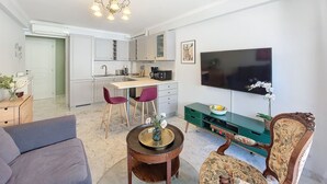 Un espace de vie compact comprenant un coin repas, une kitchenette et un téléviseur à écran plat fixé au mur.
